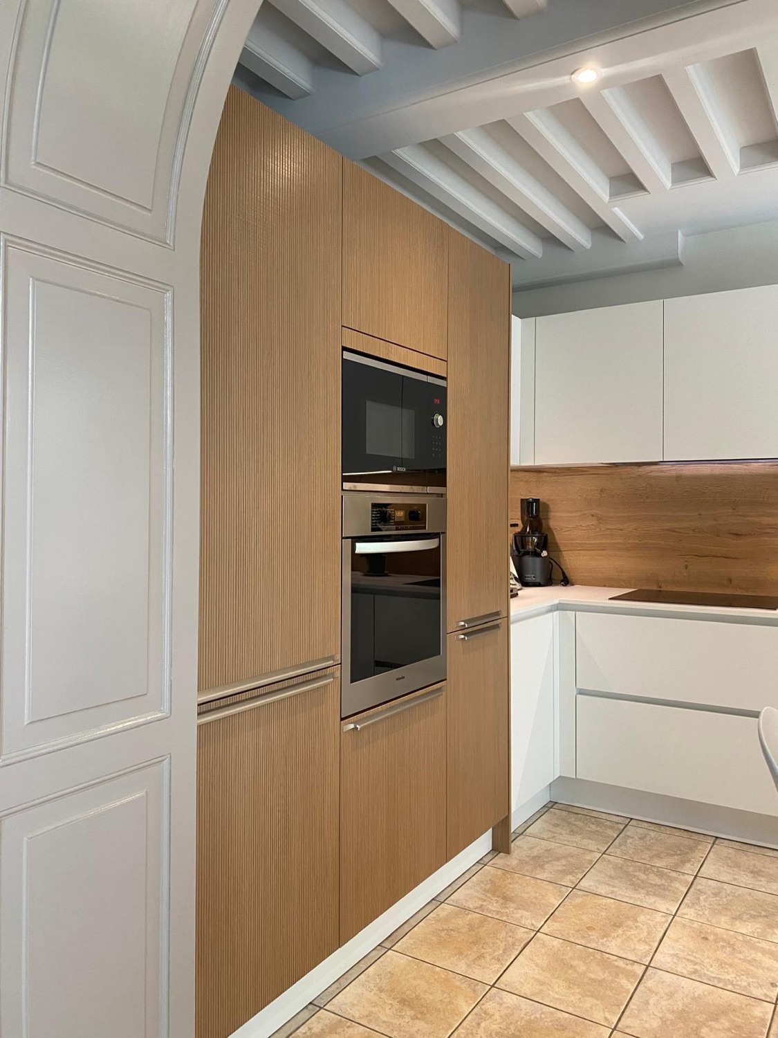 Cuisine blanche et chêne sous arche en pierre